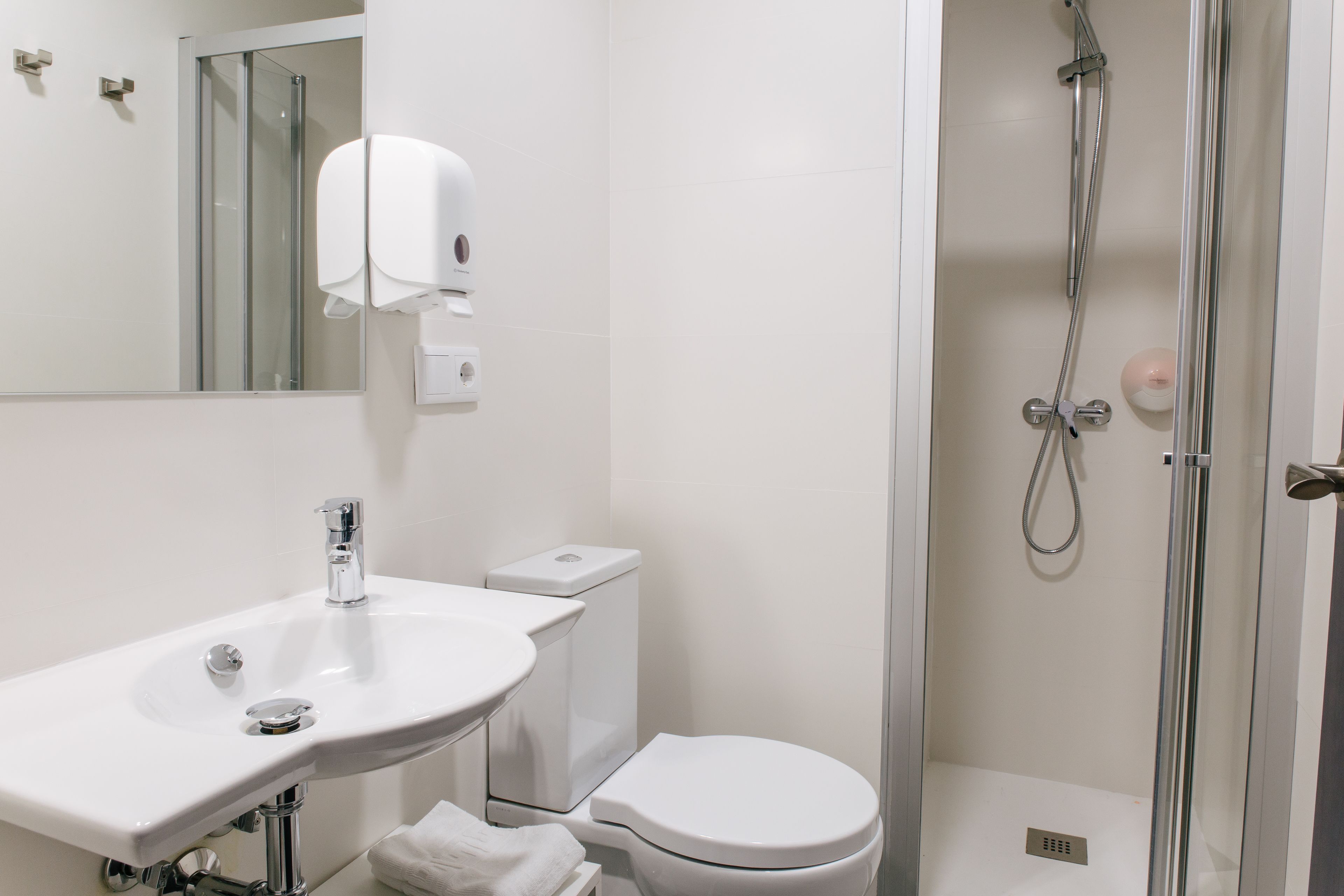 A modern bathroom with a sink, toilet, and glass-enclosed shower.