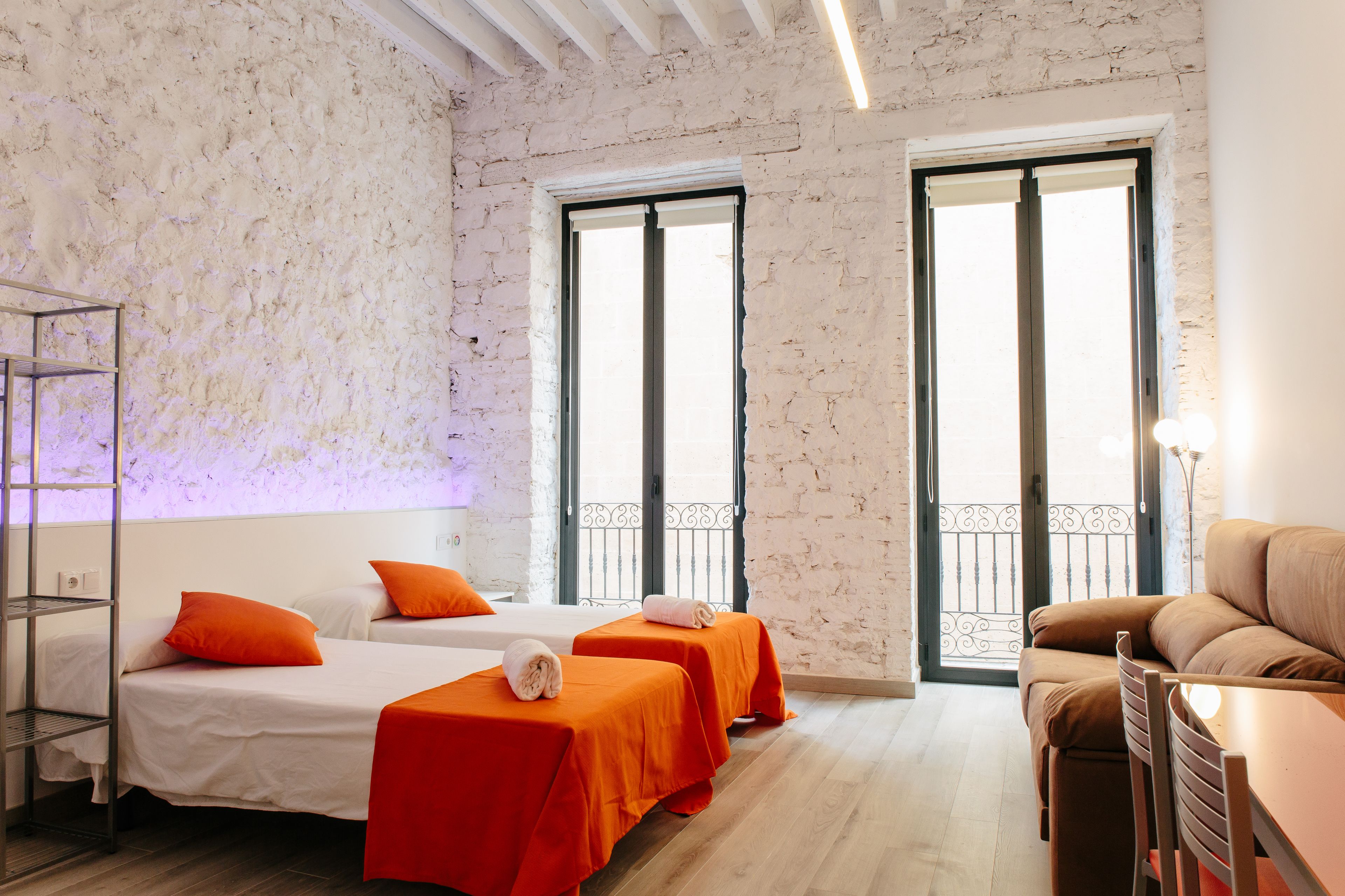 A hotel room with two beds, a sofa, a table, and a balcony.