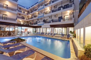 A multi-story hotel with a swimming pool, sun loungers, and a restaurant area. - Agrabella Hotel - Adults Only (Hersonissos)