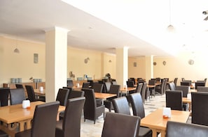 A spacious dining area with multiple tables and chairs, a clean and modern design, and a neutral color palette.
