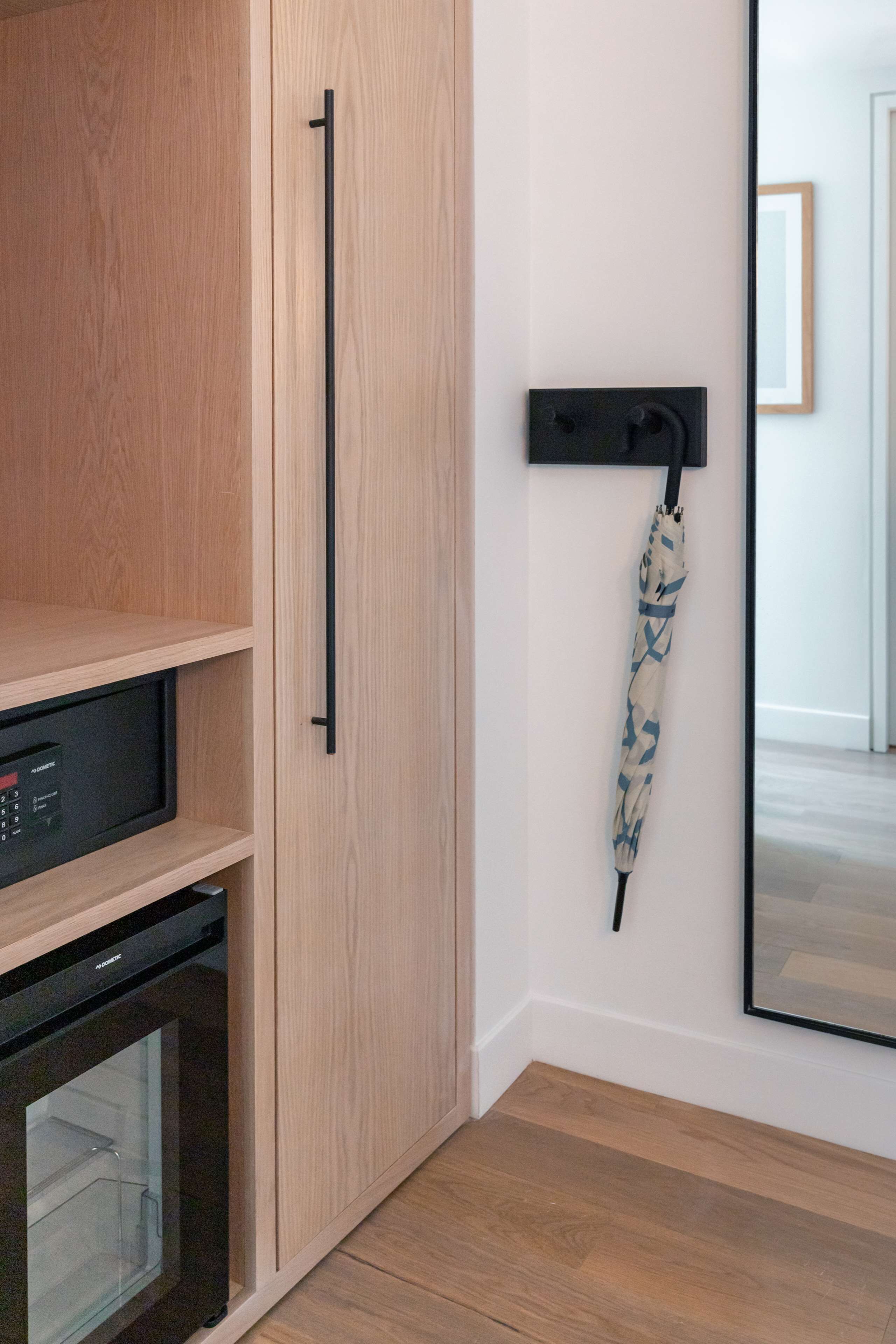 A modern kitchen with wooden cabinetry, a built-in microwave, and a black handle on the wall.