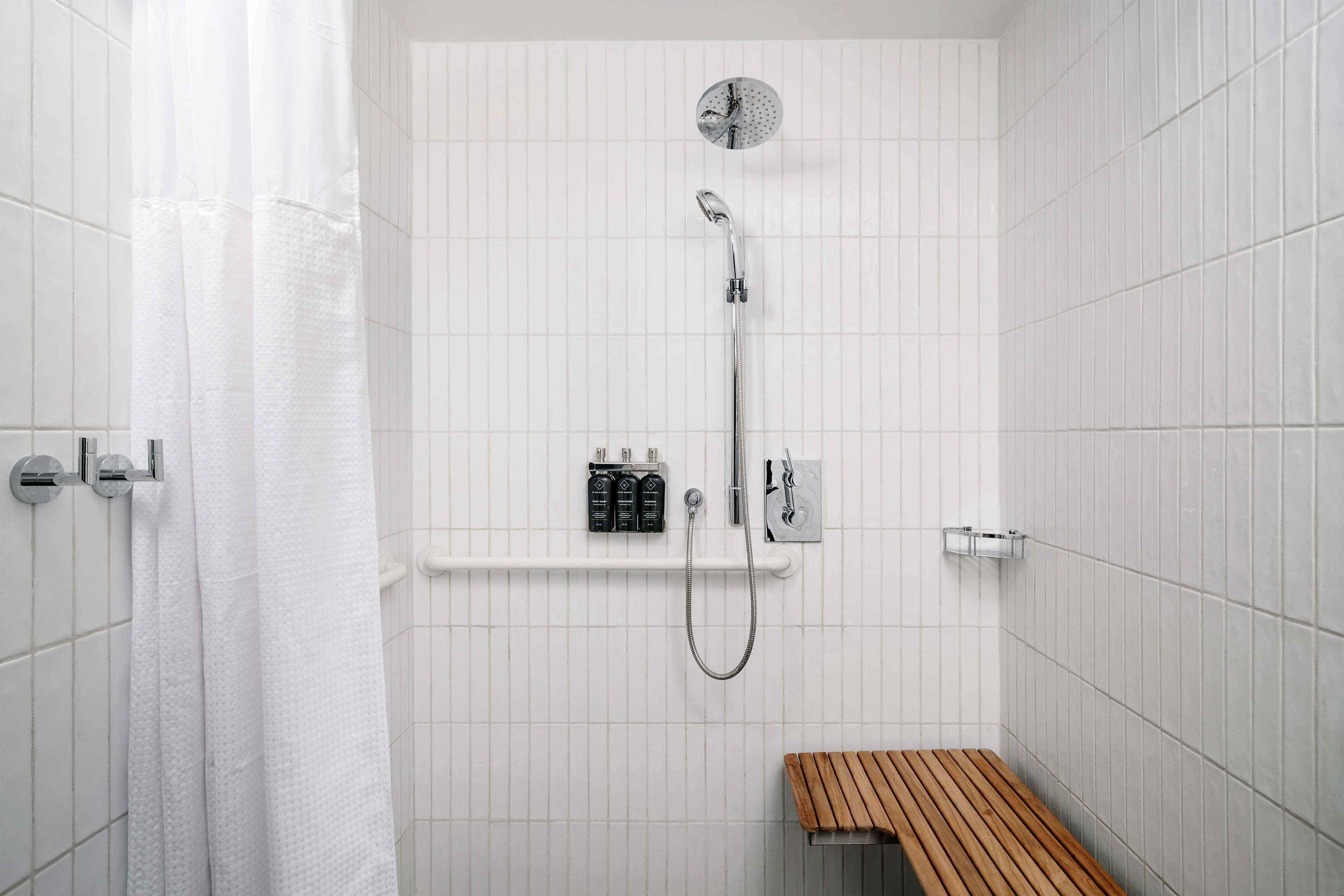 Ducha con cabezal de ducha de mano, panel de control en la pared y banco de madera.