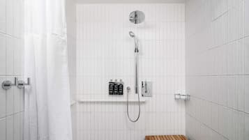 Eine Dusche mit Duschbrause, einer fest installierten Bedienung und einer hölzernen Sitzbank.