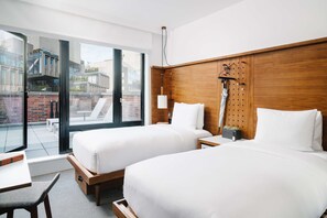 Habitación de hotel con dos camas, cabecero de madera, un ventanal grande y un balcón.