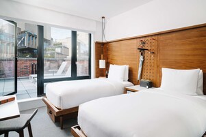 Een hotelkamer met twee bedden, een houten hoofdeinde, een groot raam en een balkon.