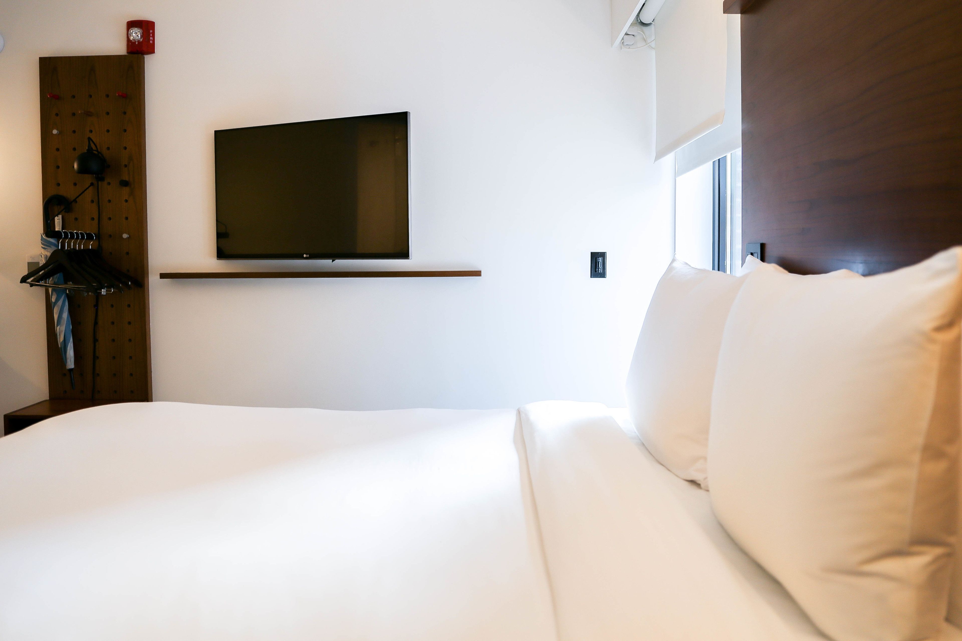 Une chambre d’hôtel avec un grand lit, un téléviseur fixé au mur et une tête de lit en bois.