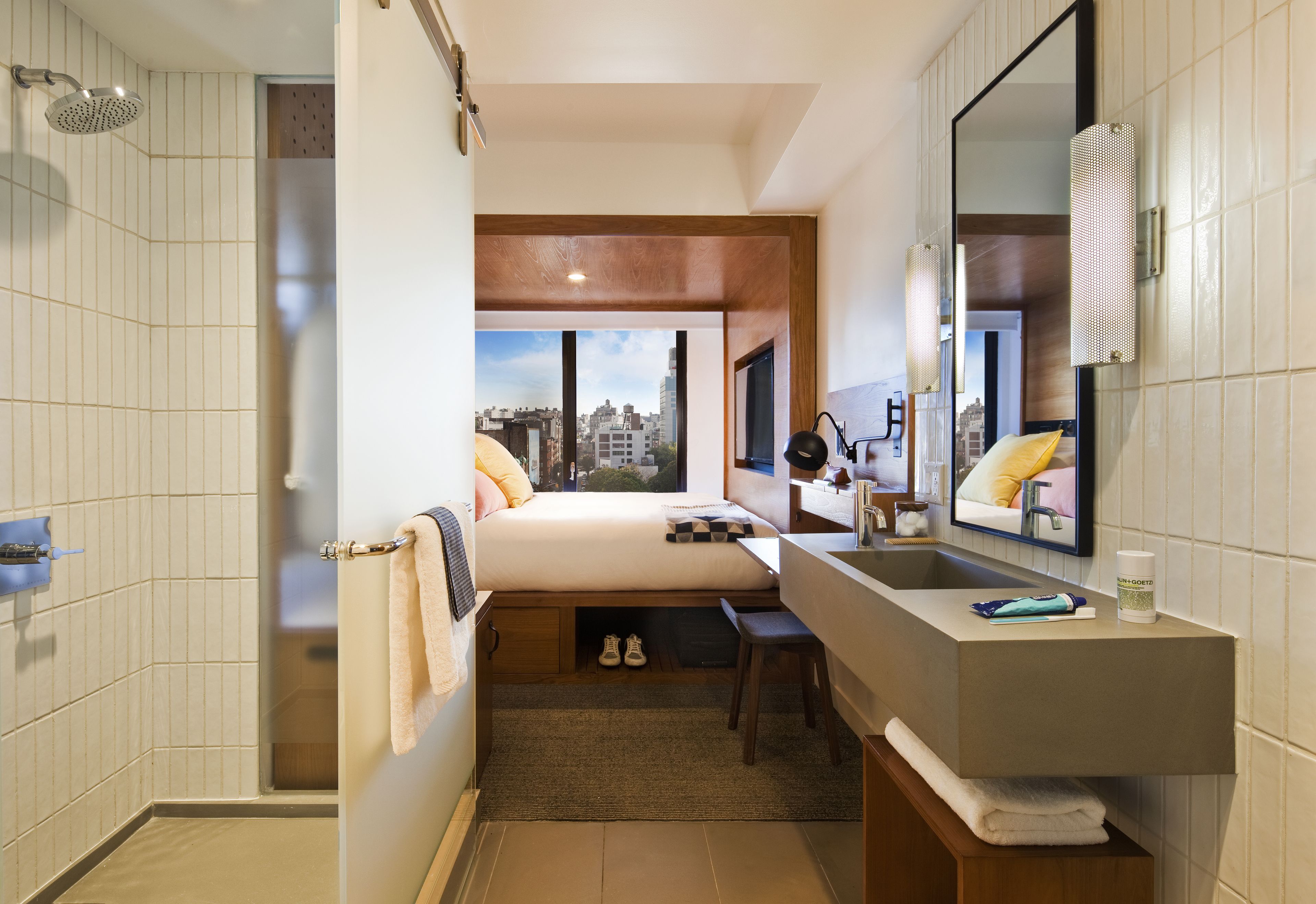 Un bany d'hotel modern amb dutxa, un vàter i un mirall gran.