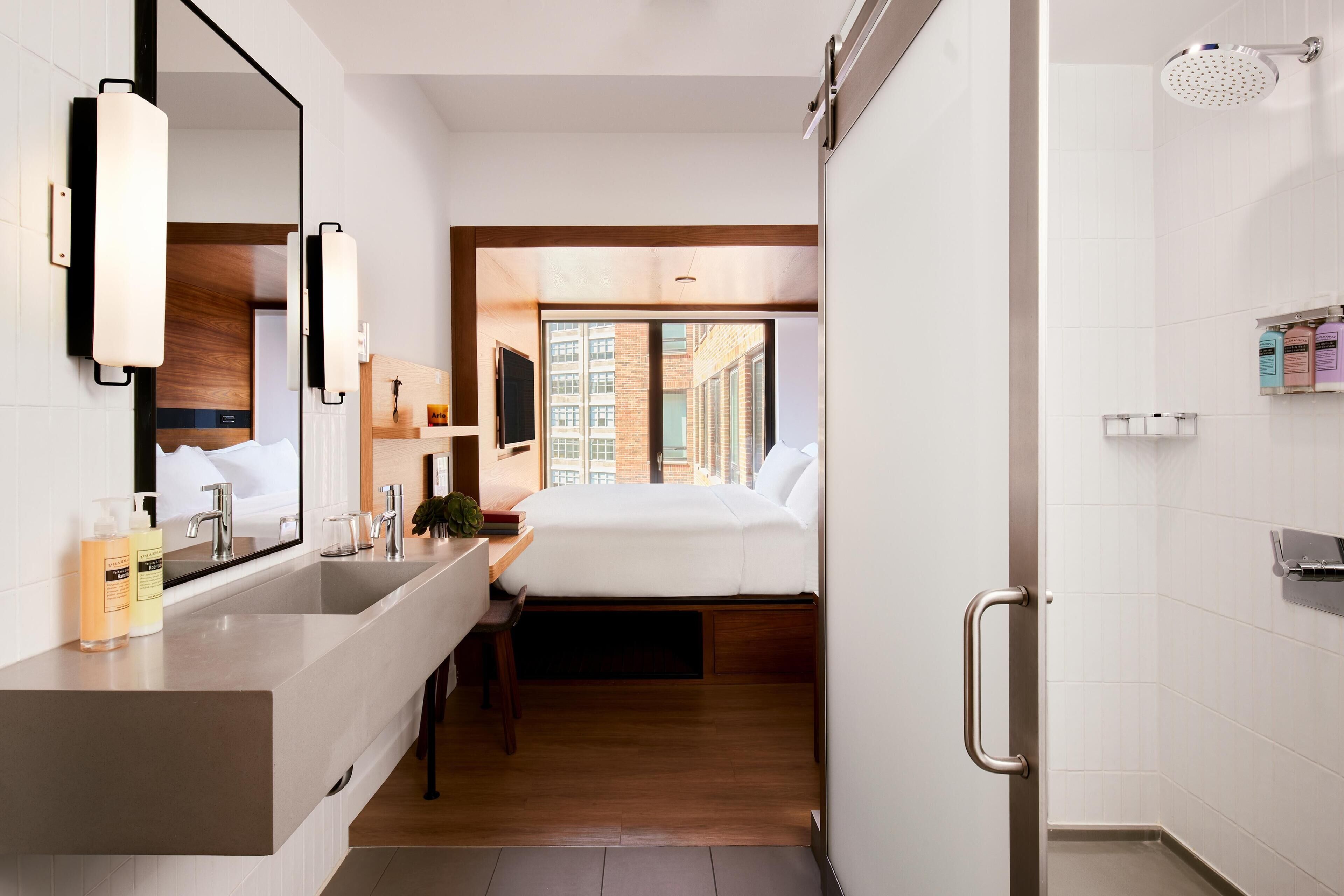 A modern bathroom with a large mirror, a sink, and a shower.