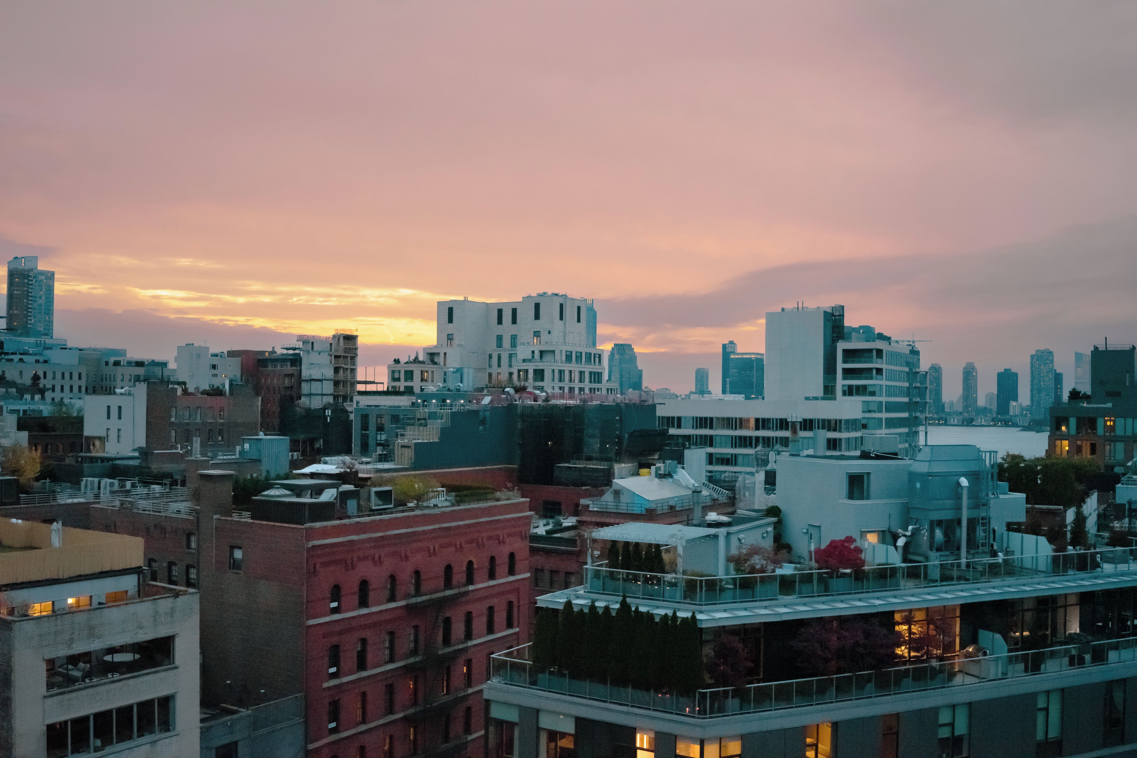 A cityscape with various buildings, including modern and older structures, under a twilight sky.