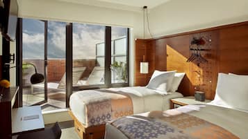 A hotel room with two beds, a desk, and a large sliding glass door leading to a balcony.
