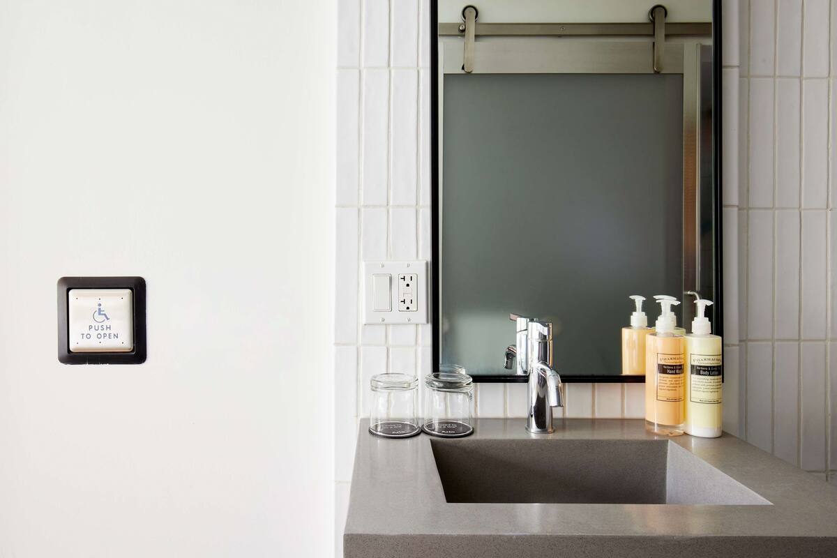 A modern bathroom with a large mirror, a sink, and two glass jars on the countertop.
