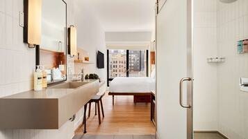 A modern bathroom with a large mirror, a sink, and a shower.