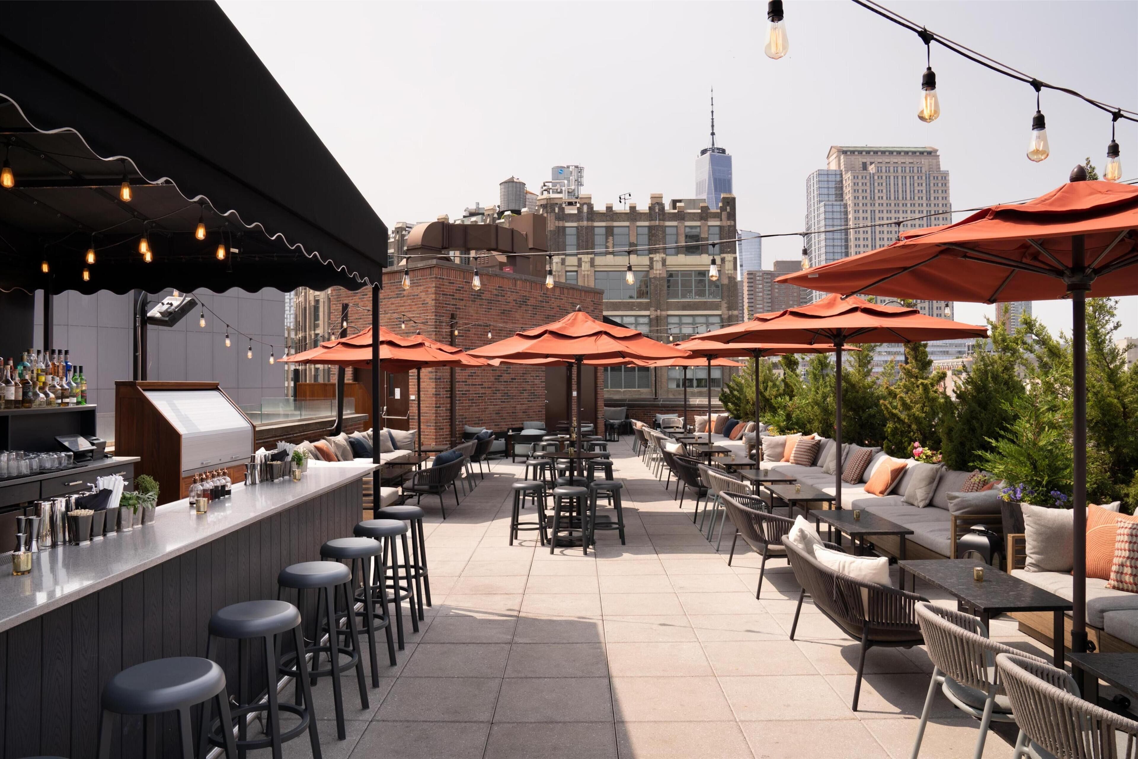 An outdoor patio with seating, a bar area, and city views.