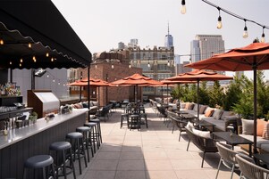 Un patio al aire libre con asientos, una zona de bar y vistas a la ciudad.