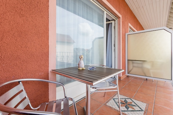 Un balcon avec une table et des chaises, un vase décoratif et une vue sur l’extérieur.