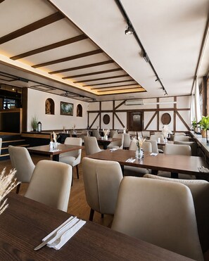 A restaurant with multiple tables and chairs, wooden beams on the ceiling, and wall-mounted artwork. - Hotel Weinhaus Wiedemann (Ginsheim-Gustavsburg)