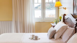 A hotel room with a bed, a bedside table with a lamp, and a window with curtains. - Hotel La Galería (San Sebastián)