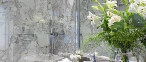 A modern bathroom with a marble sink, a glass shower enclosure, and a mirror reflecting the bathroom's interior.