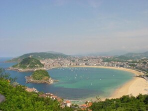 A coastal cityscape with a bay, a beach, and a densely populated urban area.