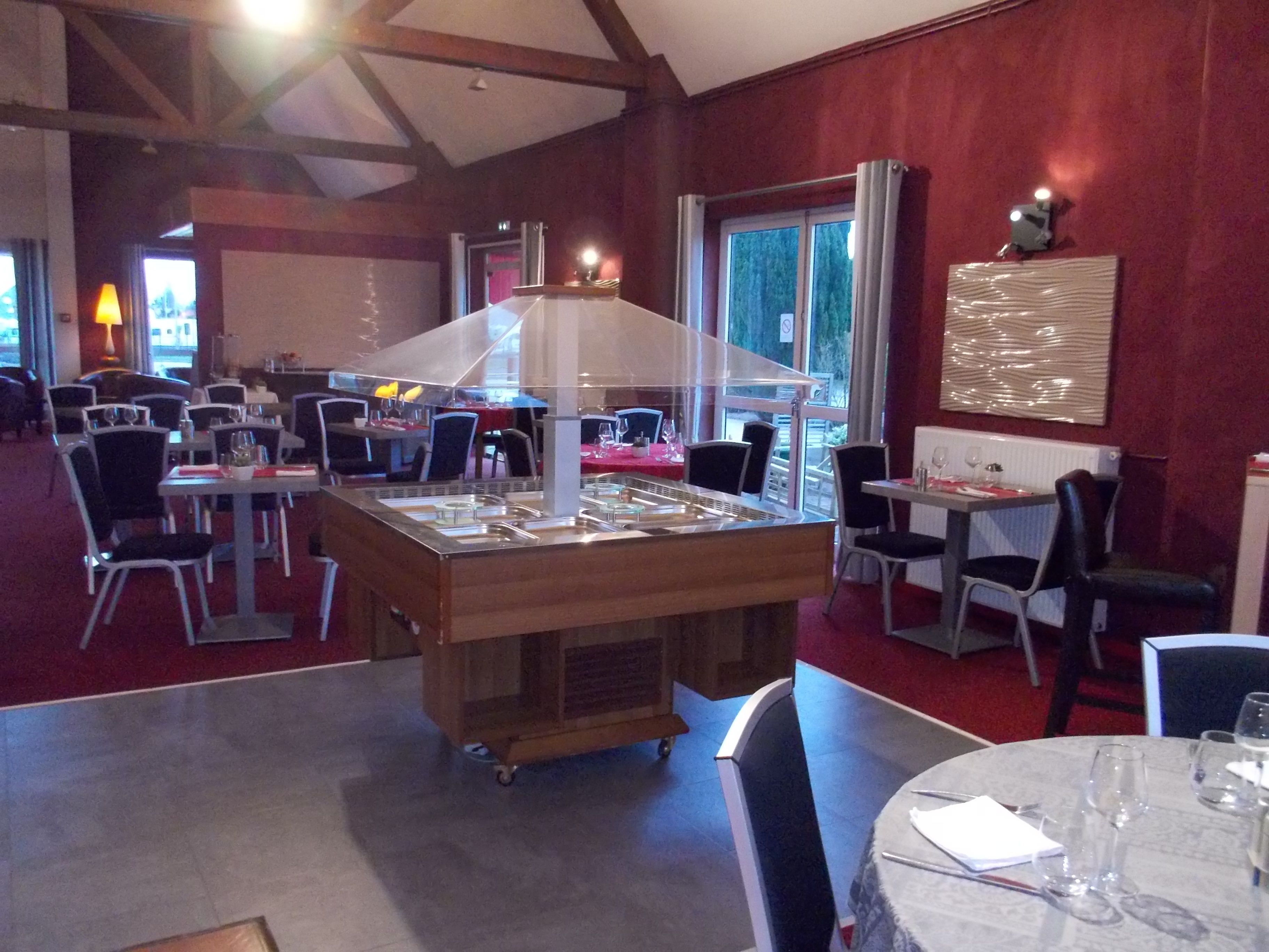 A restaurant with a central bar area, multiple tables, and chairs.