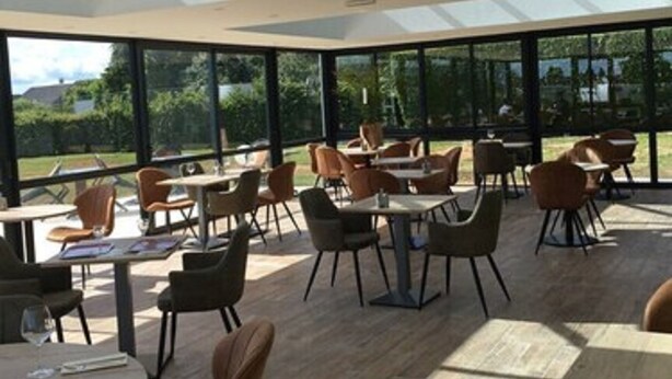 A spacious indoor area with a high ceiling and skylights, featuring multiple tables and chairs arranged for dining or socializing. - Hôtel le Pavillon de Rouen (Franqueville-Saint-Pierre)