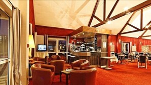 A hotel lobby with leather sofas, a bar area, and a large window. - Hôtel le Pavillon de Rouen (Franqueville-Saint-Pierre)