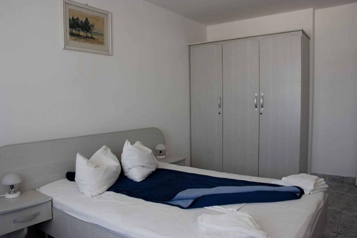 A bedroom with a bed, a nightstand, a wardrobe, and a painting on the wall.