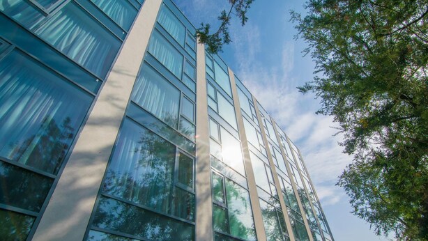 Un edificio moderno con amplios ventanales de vidrio y un cielo despejado.
