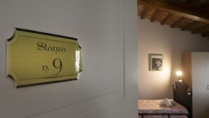 A room with a bed, a bedside table, a lamp, and a door with a sign reading "Stanza n. 9". - Affittacamere Il Granaio (Lucca)