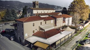 A multi-story building with a flat roof, a covered outdoor seating area, and a parking lot. - Affittacamere Il Granaio (Lucca)