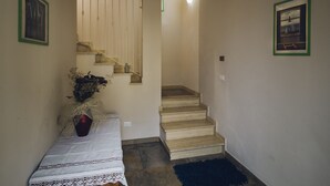 A hallway with a wooden bench, a vase with flowers, a staircase, and two framed pictures on the walls. - Affittacamere Il Granaio (Lucca)