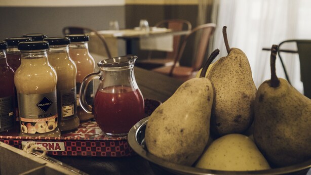 A dining table with a bowl of pears, a pitcher of juice, and several bottles of sauces. - Affittacamere Il Granaio (Lucca)