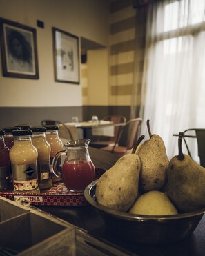 A dining table with a bowl of pears, a pitcher of juice, and several bottles of sauces. - Affittacamere Il Granaio (Lucca)