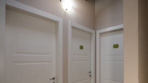 A hallway with three white doors, each marked with a number. The floor is wooden, and the walls are painted in a light color. - Affittacamere Il Granaio (Lucca)