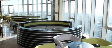 A modern lounge with tiered seating and large windows offering city views.
