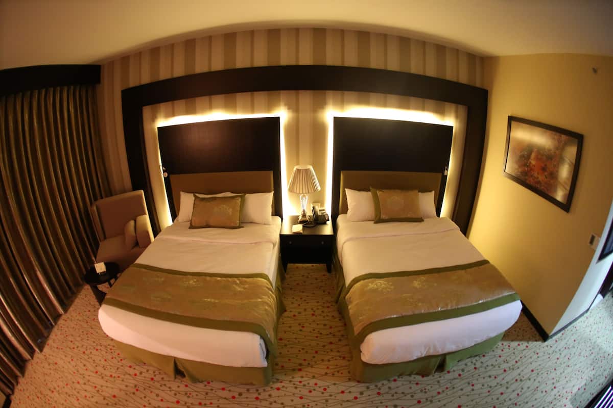 Une chambre d’hôtel avec deux lits, une table de chevet, une lampe et une chaise.