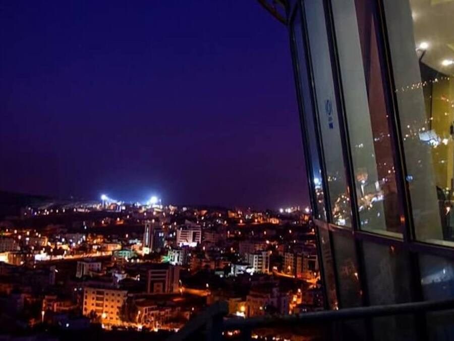 Vista nocturna de un paisaje urbano desde un rascacielos con amplias ventanas.