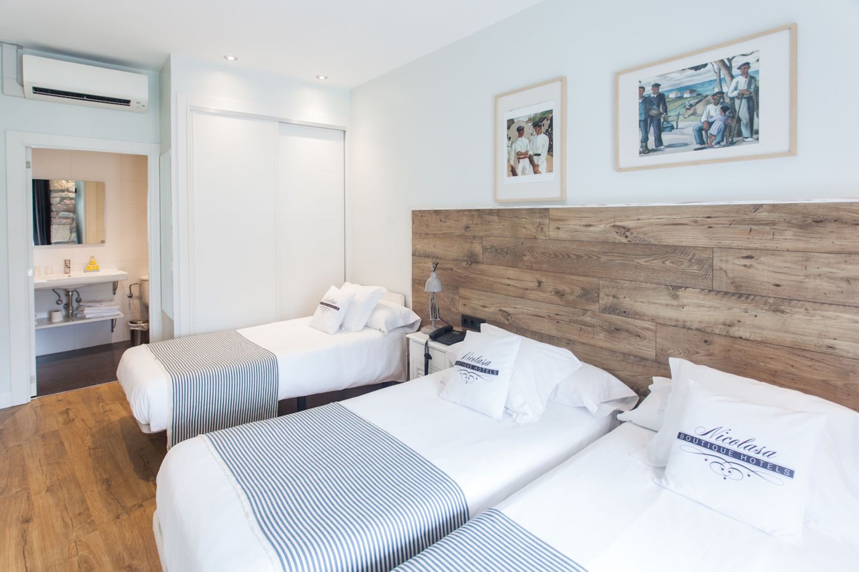 A hotel room with two beds, a wooden headboard, a small desk, and a mirror.