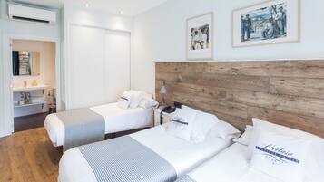 Een hotelkamer met twee bedden, een houten hoofdbord, een klein bureau en een spiegel.