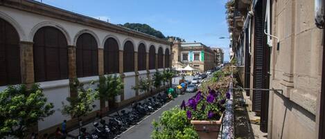 A narrow street with parked scooters and a row of buildings with arched windows and balconies.