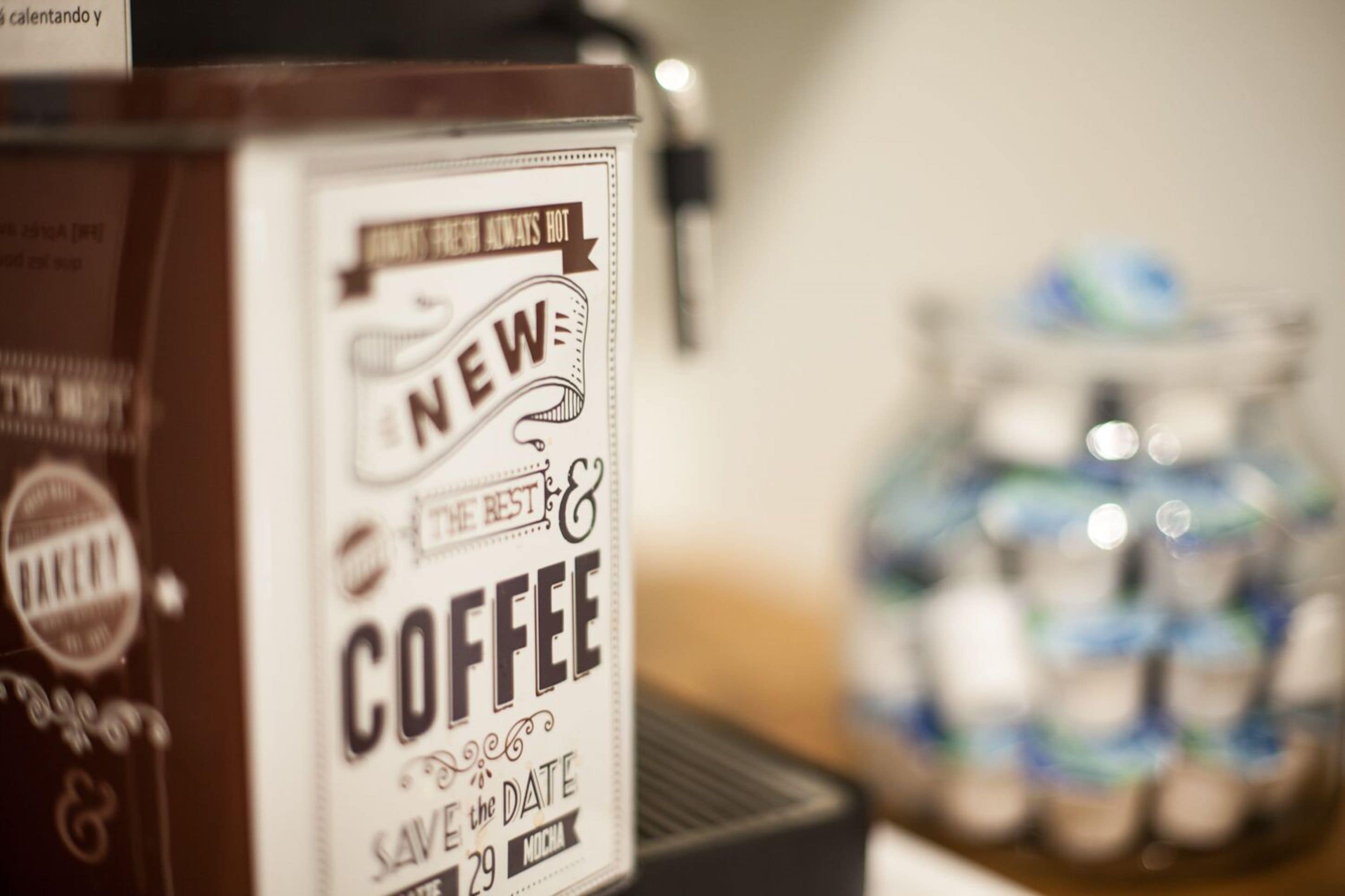 Una máquina de café con una etiqueta que dice 'NUEVO CAFÉ GUARDEN LA FECHA'.