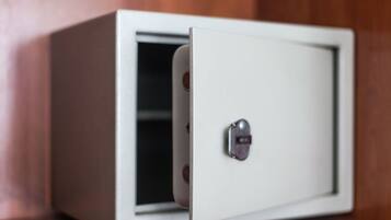 Una caja fuerte blanca con cerradura de combinación, ubicada frente a un fondo de madera.