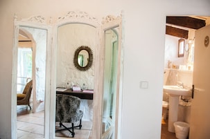 Una habitación con un espejo, una silla y vistas a otra habitación.