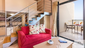 Ein modernes Interieur mit einem roten Sofa, einer Treppe, einem Essbereich und Blick durch eine Glastür.