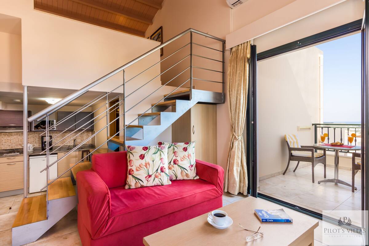 A modern interior with a red sofa, a staircase, a dining area, and a view through a glass door.