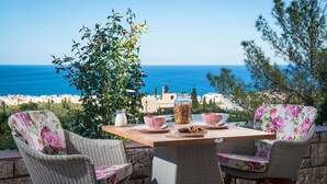 Ein Korbstuhl-Tisch mit Stühlen und Blick aufs Meer.