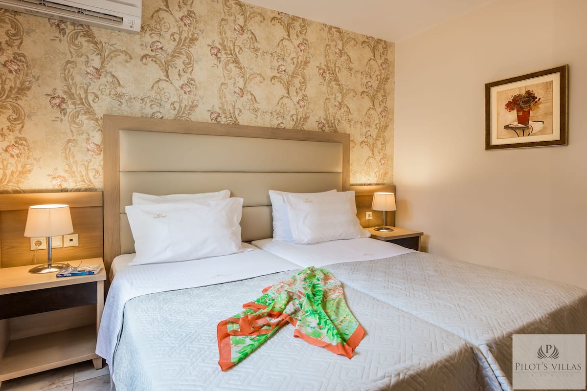 A hotel room with a large bed, two bedside tables with lamps, a decorative wall, and a framed picture on the wall.