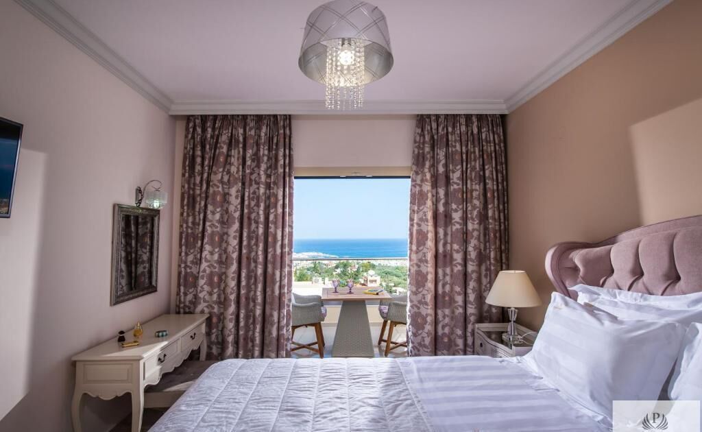 Una camera d'albergo con un letto, una scrivania, una sedia, una lampada e vista sull'oceano.