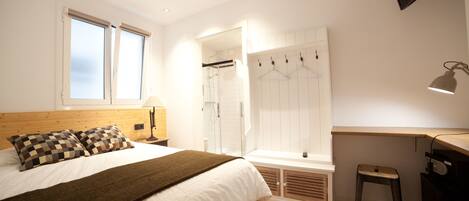 A bedroom with a bed, a desk, a chair, a TV, and a walk-in closet.