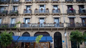 A building with a sign reading "Casa Nicolasa" and a storefront with a blue awning.